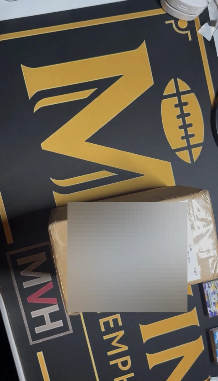 A sealed parcel from an inbound collection resting on the Mint By Memphis mat, its shipping label blurred to protect the seller's privacy.