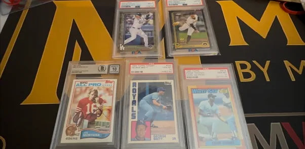 Five graded baseball and football cards from a newly arrived collection laid out on the Mint By Memphis mat.