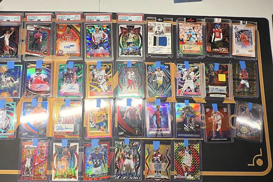 High-end graded slabs and autographed football and basketball cards laid out on the Mint by Memphis mat for verification