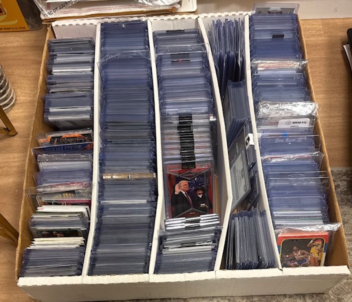 Cards sorted into rows of toploaders in a storage box